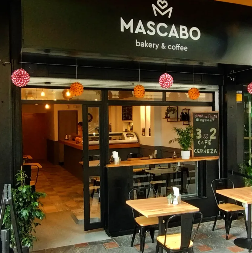 Fachada de Mascabo de día, con farolillos de colores y la terraza montada